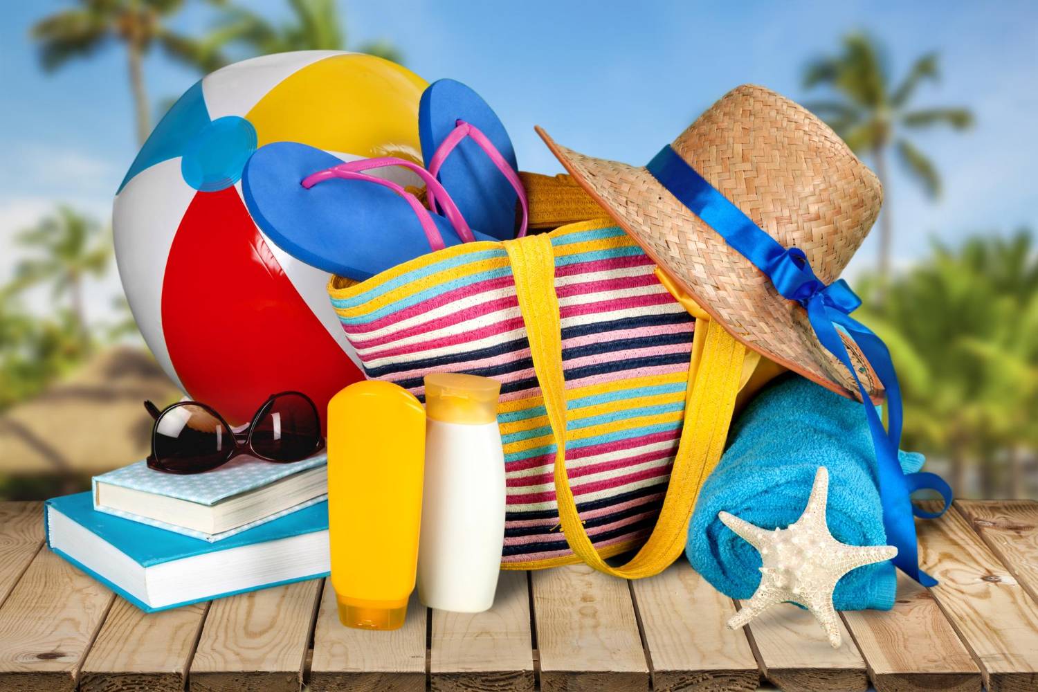 A colorful beach bag filled with flip-flops, a towel, a straw hat, sunscreen, and a starfish, next to a beach ball, books, and sunglasses. Day trip to Shell Island essentials.