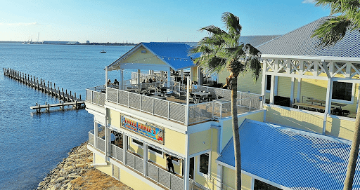 An aerial view of Uncle Ernie's in Panama City, a waterfront restaurant with a spacious deck overlooking the calm bay, surrounded by palm trees.