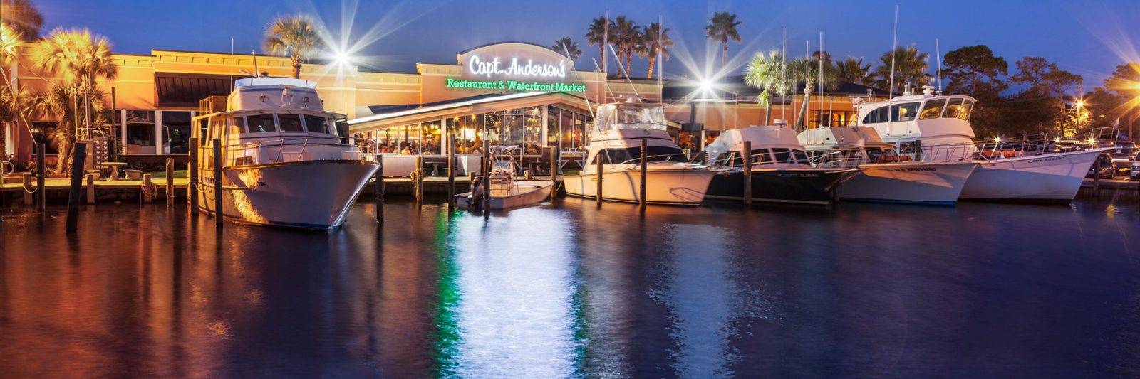Capt. Anderson's Restaurant illuminated at night, showcasing docked boats and vibrant waterfront dining, part of Panama City's most scenic waterfront restaurants.